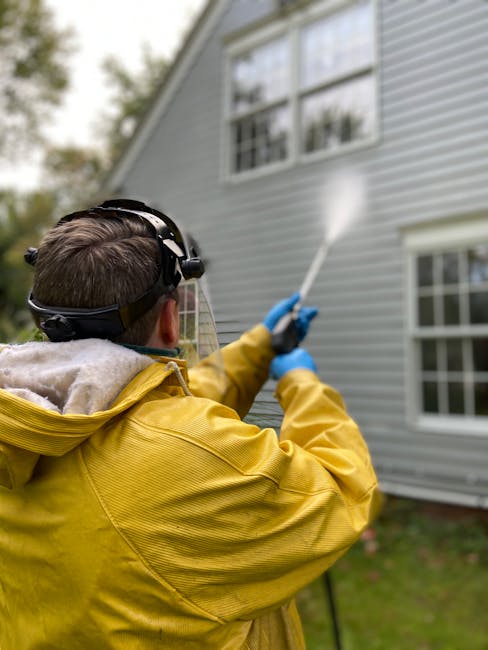 Back View of a Person Pressure Washing a House